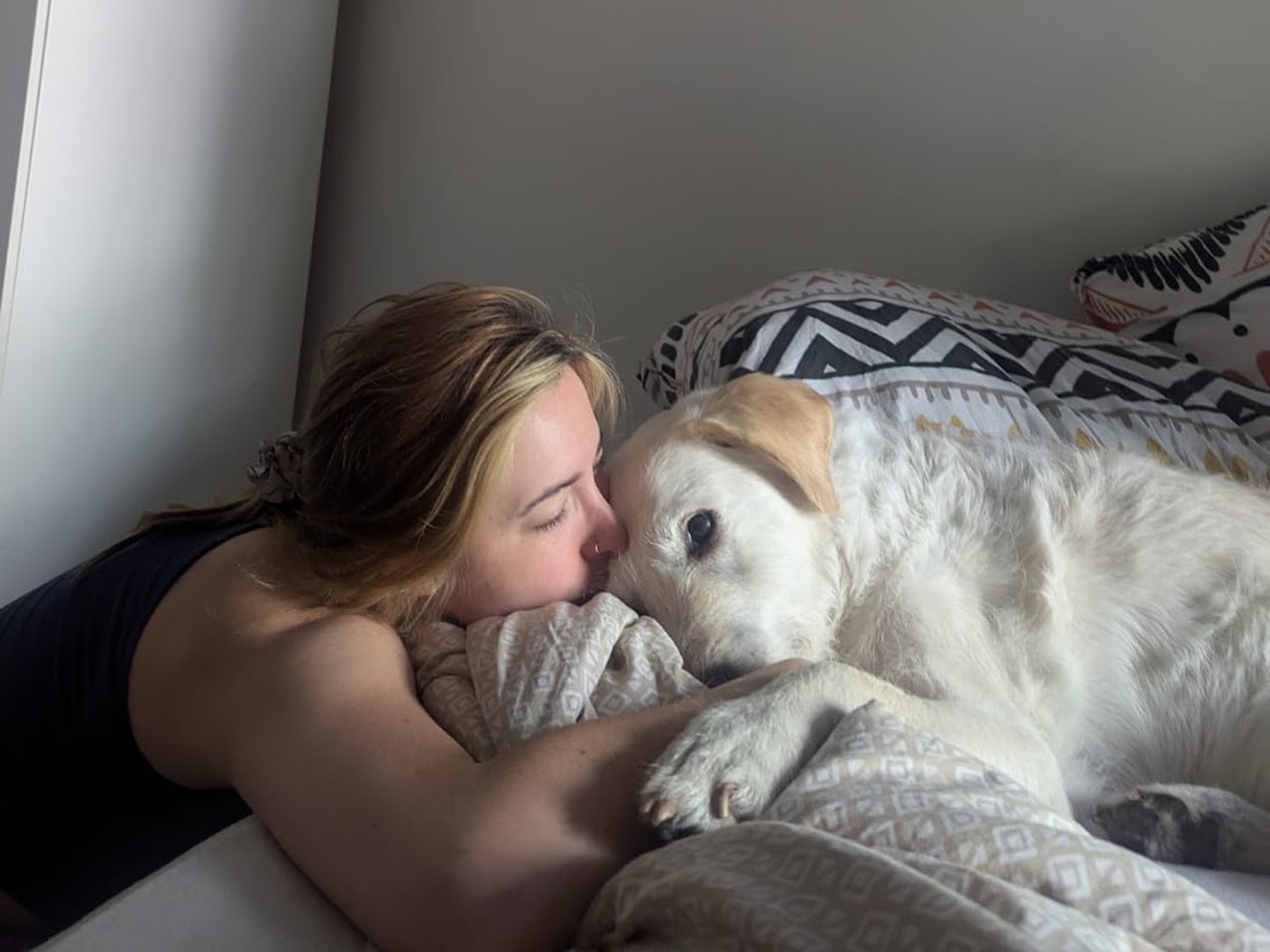 Aga cuddling Spock, a white dog, on a bed